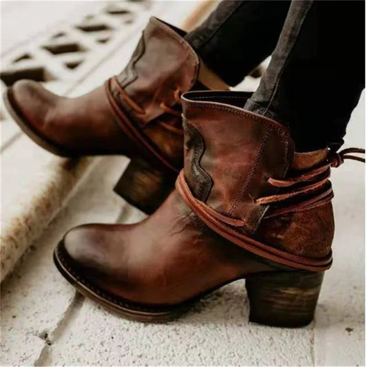 Braune Lederstiefeletten mit Absatz, lässiger Westernstil, dekorative Schnürung, getragen auf hellem Boden. Perfekt für Herbstmode und Outdoor-Looks.