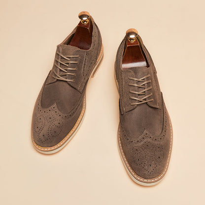 Braune Wildleder-Brogues mit Lochmuster und Holzschuhspanner auf beigem Hintergrund. Elegante Herrenschuhe, stilvoll und klassisch.