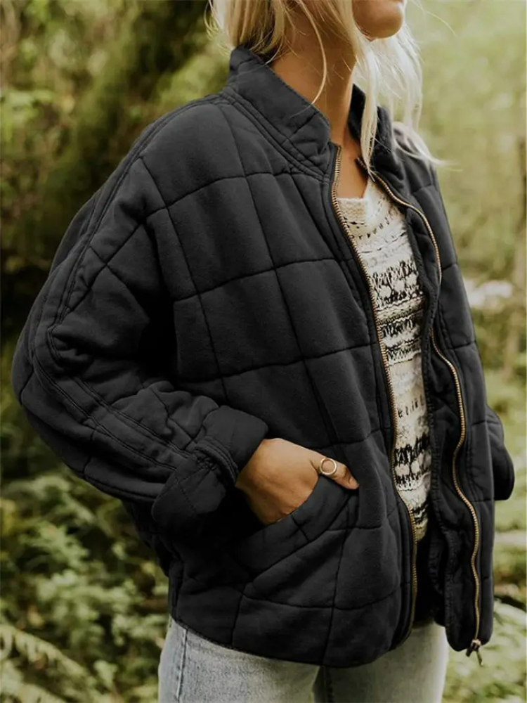Frau in schwarzer Steppjacke und Strickpullover im Freien, lässiger Herbstlook, Mode für kühle Tage, Naturhintergrund.
