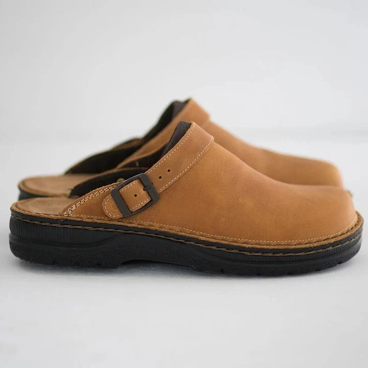 Braune Leder-Clogs mit schwarzer Sohle und verstellbarem Riemen, seitlich fotografiert. Bequeme, modische Schuhe für Damen und Herren.