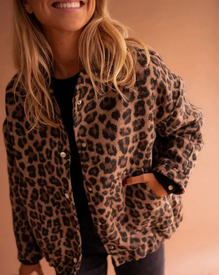 Frau trägt Leopardenmuster-Jacke, lächelt, Hand in der Tasche. Modetrend, Damenmode, Herbstoutfit, stilvoll, lässig.