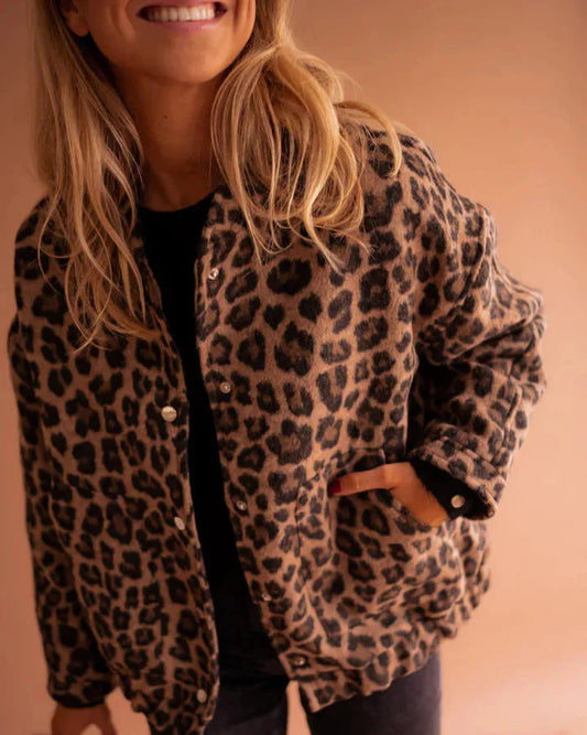 Frau trägt Leopardenmuster-Jacke, lächelt, Hand in der Tasche. Modetrend, Damenmode, Herbstoutfit, stilvoll, lässig.