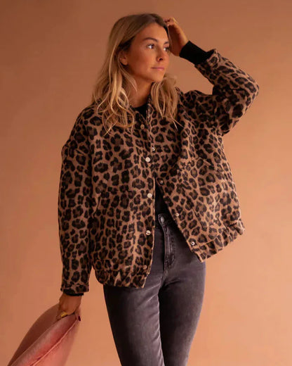 Frau in Leopardenmuster-Jacke, blonde Haare, steht vor beigem Hintergrund. Modetrend, Herbstmode, Damenjacke, lässiger Stil, Tiermuster.