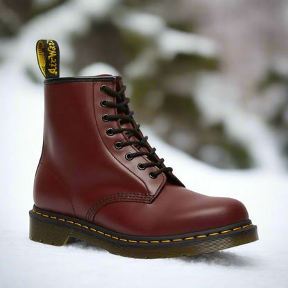 Burgunderroter Dr. Martens Stiefel im Schnee, ikonisches Design, gelbe Nähte, robuste Sohle, Wintermode, Outdoor-Boots, Lederstiefel.