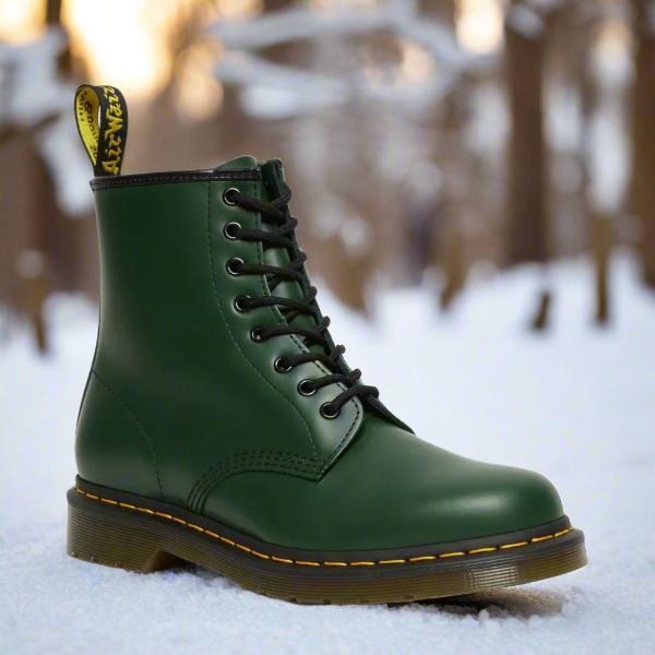 Grüner Dr. Martens Stiefel im Schnee, klassische Schnürstiefel, robustes Leder, gelbe Nähte, Wintermode, Outdoor-Boots, ikonisches Design.