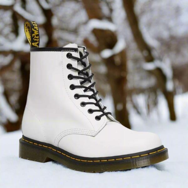 Weiße Dr. Martens Stiefel im Schnee, klassische Schnürstiefel mit gelber Naht, Wintermode, robuste Lederstiefel, Outdoor-Footwear.