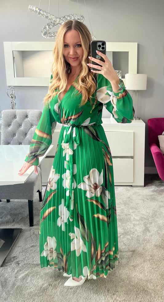 Frau in grünem, geblümtem Maxikleid macht Selfie im modernen Wohnzimmer. Elegantes Design, modische Kleidung, stilvolle Inneneinrichtung.