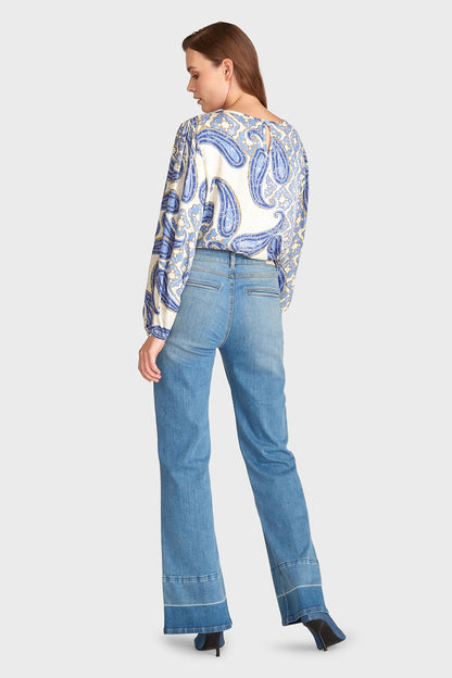 Frau in blauer Jeans und gemusterter Bluse, Rückansicht. Modetrend 2023, lässiger Look, Damenmode, stilvolle Freizeitkleidung.