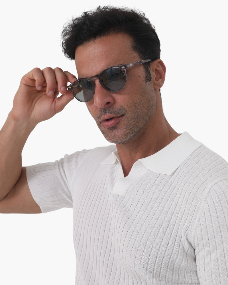 Mann mit Sonnenbrille und weißem Polohemd, modisch, selbstbewusst, isoliert auf weißem Hintergrund. Ideal für Mode- und Accessoire-Werbung.