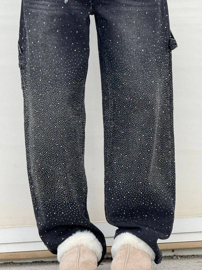 Dunkle Jeans mit funkelnden Strasssteinen, kombiniert mit beigen Stiefeln mit Fellbesatz. Modetrend, Glitzer-Jeans, Wintermode.