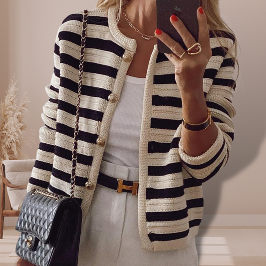 Dame in gestreifter Strickjacke, weißem Top und Hose, mit schwarzer Lederhandtasche. Modetrend, eleganter Look, Herbstmode 2023.