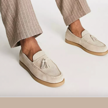 Helle Mokassins mit Quasten, getragen von einer Person in gestreiften Hosen. Stilvolle Herrenschuhe, ideal für elegante Freizeitoutfits.