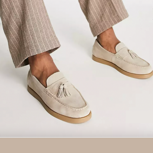 Helle Mokassins mit Quasten, getragen von einer Person in gestreiften Hosen. Stilvolle Herrenschuhe, ideal für elegante Freizeitoutfits.