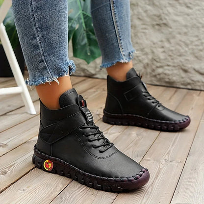 Schwarze Damen-Sneaker aus Leder, kombiniert mit blauen Jeans. Modische, bequeme Schuhe für Herbst und Winter auf Holzboden.