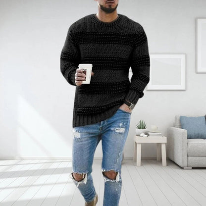 Mann in modernem Wohnzimmer trägt schwarzen Strickpullover und zerrissene Jeans, hält Kaffeetasse. Stilvolle Herrenmode, lässiger Look.