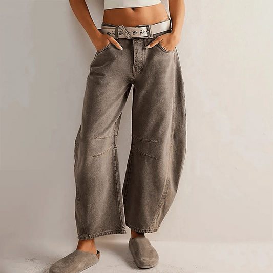 Frau in grauer, weiter Jeanshose mit weißem Gürtel und beigen Slippern, lässiger Look, Mode für Damen, trendige Streetwear, entspannter Stil.