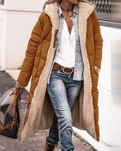 Frau in braunem, langem Wintermantel mit weißem Futter, Jeans und weißem Hemd. Modischer Herbst-Look, lässiger Stil, Outdoor-Bekleidung.