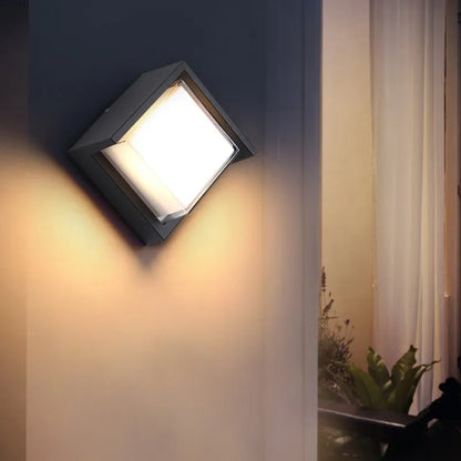 Moderne quadratische Außenwandleuchte mit warmweißem Licht an einer Hauswand, ideal für Gartenbeleuchtung und energiesparende Außenbeleuchtung.