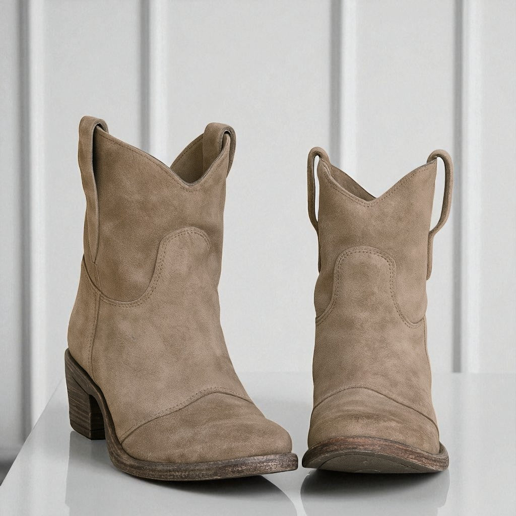 Beige Wildleder-Cowboystiefel mit Blockabsatz auf weißem Hintergrund. Modische Westernstiefel für Damen, ideal für Herbst-Outfits und lässigen Stil.