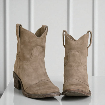 Beige Wildleder-Cowboystiefel mit Blockabsatz auf weißem Hintergrund. Modische Westernstiefel für Damen, ideal für Herbst-Outfits und lässigen Stil.