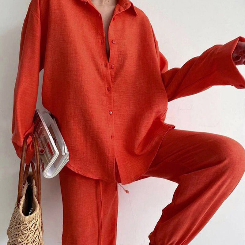 Frau in rotem Leinenhemd und Hose, hält Zeitschrift und Korbtasche. Modetrend, lässiger Stil, Sommeroutfit, Damenmode, rote Kleidung.