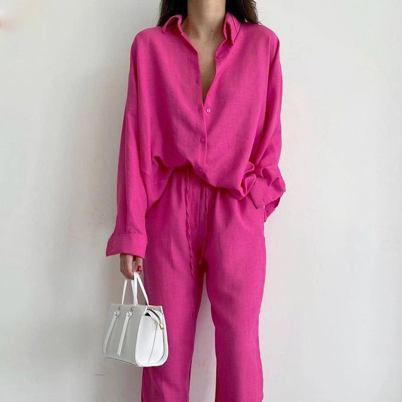 Frau in leuchtend pinkem Anzug mit weißer Handtasche vor weißem Hintergrund. Modetrend, Damenmode, eleganter Look, stilvolle Kleidung.