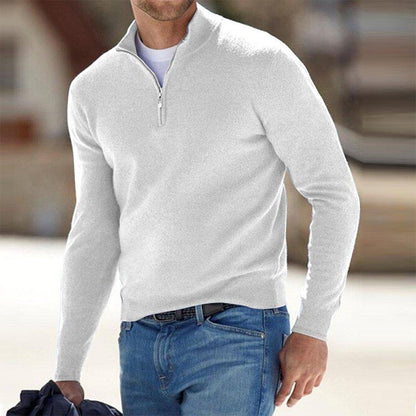 Mann in weißem Pullover mit Reißverschluss und blauer Jeans, hält Jacke. Modischer Freizeitlook, ideal für kühle Tage. Herrenmode, stilvoll und bequem.