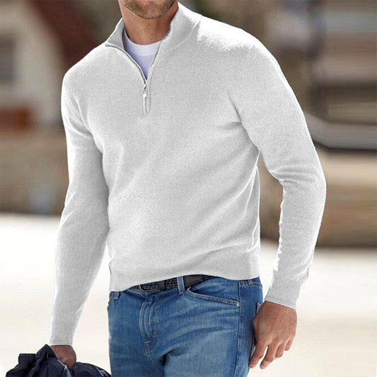Mann in weißem Pullover mit Reißverschluss und blauer Jeans, hält Jacke. Modischer Freizeitlook, ideal für kühle Tage. Herrenmode, stilvoll und bequem.