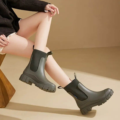 Damenbeine in olivgrünen Chelsea Boots mit dicker Sohle, modisch und robust, ideal für Herbstmode. Perfekt für stilvolle Outdoor-Aktivitäten.