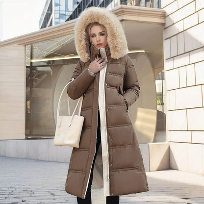 Frau in braunem Daunenmantel mit Fellkapuze, hält weiße Handtasche, steht vor moderner Architektur. Wintermode, stilvoll, elegant.