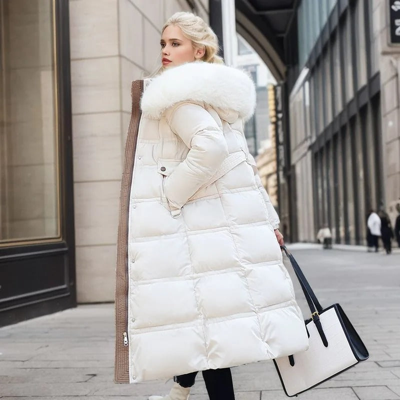 Blonde Frau in weißem Daunenmantel mit Fellkapuze, hält schwarze und weiße Handtasche, steht auf städtischer Straße. Wintermode, eleganter Stil.
