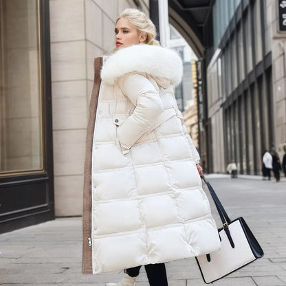 Blonde Frau in weißem Daunenmantel mit Fellkapuze, hält schwarze und weiße Handtasche, steht auf städtischer Straße. Wintermode, eleganter Stil.