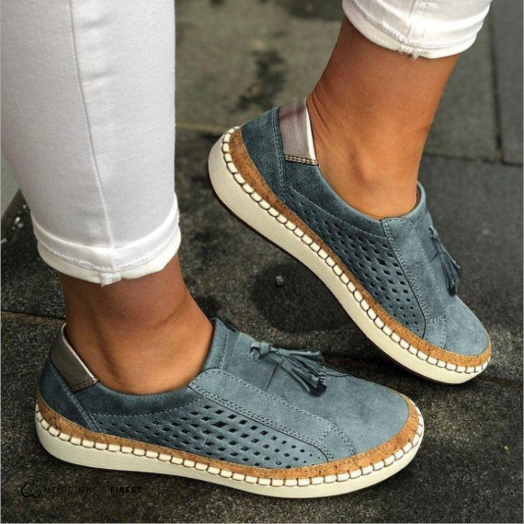 Damen Sneaker in Blau mit Lochmuster und Fransen, kombiniert mit weißen Hosen. Bequeme Freizeitschuhe für den Alltag, modisch und stilvoll.