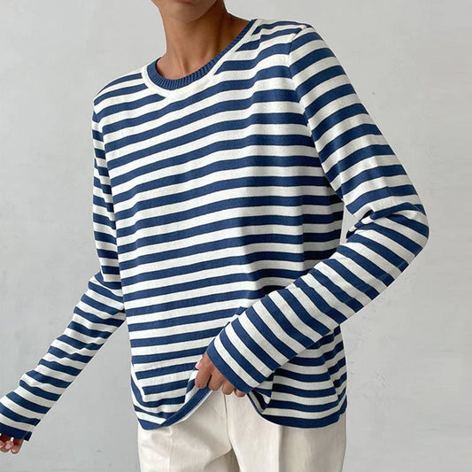 Person in gestreiftem blau-weißem Langarmshirt, lässiger Stil, modisch, minimalistisch, vor grauem Hintergrund. Ideal für Freizeitmode.