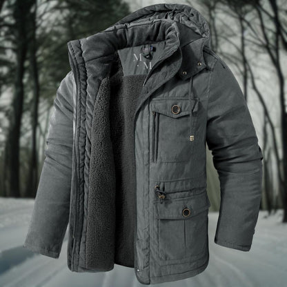Graue Winterjacke mit Kapuze und Fleece-Innenfutter, ideal für kalte Temperaturen. Perfekt für Outdoor-Aktivitäten im Winterwald.