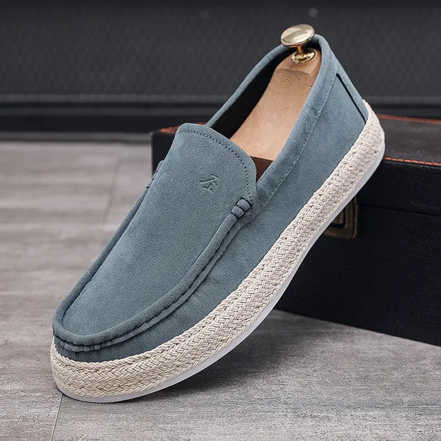 Blaue Herren-Slipper aus Wildleder mit weißer Gummisohle und geflochtenem Juteband, elegant und bequem, ideal für Freizeit und Sommermode.
