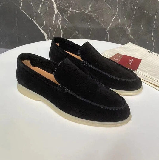 Schwarze Wildleder-Loafer für Herren auf weißem Tisch, elegante Freizeitschuhe mit beiger Sohle, ideal für stilvolle Anlässe.