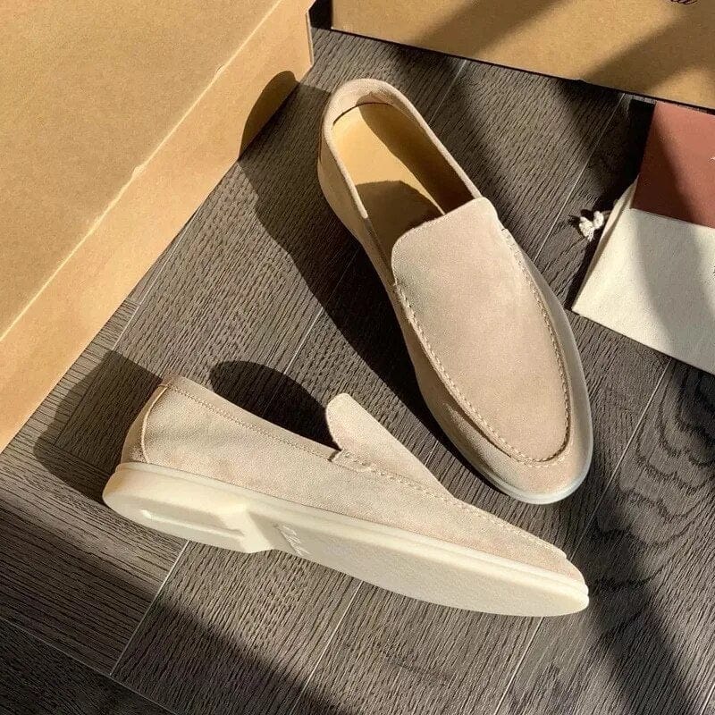 Beige Wildleder-Slipper auf Holzboden, elegantes Design, ideal für Herrenmode. Perfekt für Freizeit- und Business-Looks. Hochwertige Verarbeitung.
