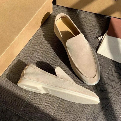 Beige Wildleder-Slipper auf Holzboden, elegantes Design, ideal für Herrenmode. Perfekt für Freizeit- und Business-Looks. Hochwertige Verarbeitung.