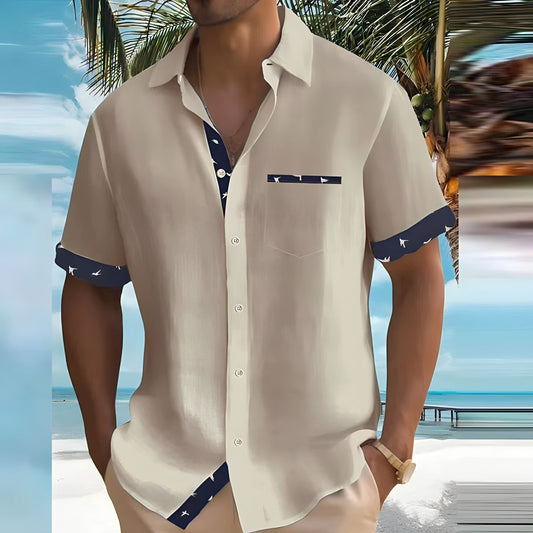 Mann in beiger Sommerhemd mit blauem Muster, steht am Strand unter Palmen. Perfekte Kleidung für tropische Urlaubsziele und Strandmode.