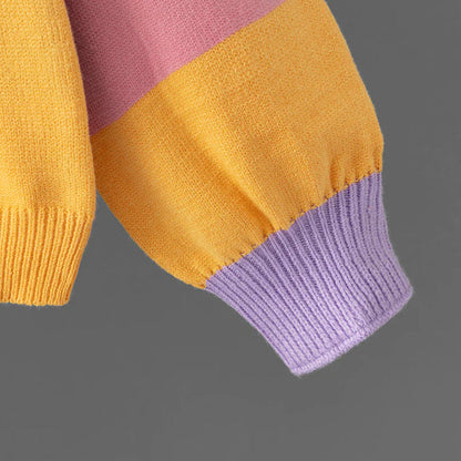 Bunter Strickpullover-Ärmel in Gelb, Rosa und Lila auf grauem Hintergrund. Modetrend, Herbstmode, Strickwaren, Farbkombination.