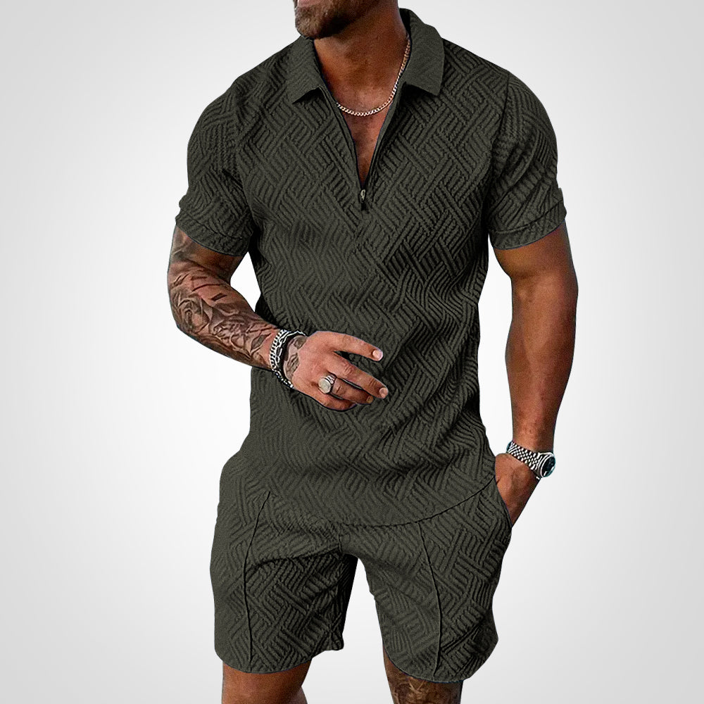 Mann in dunkelgrünem, gemustertem Poloshirt und Shorts, tätowierter Arm, trägt Schmuck. Sommermode, Herrenbekleidung, stilvoller Look.