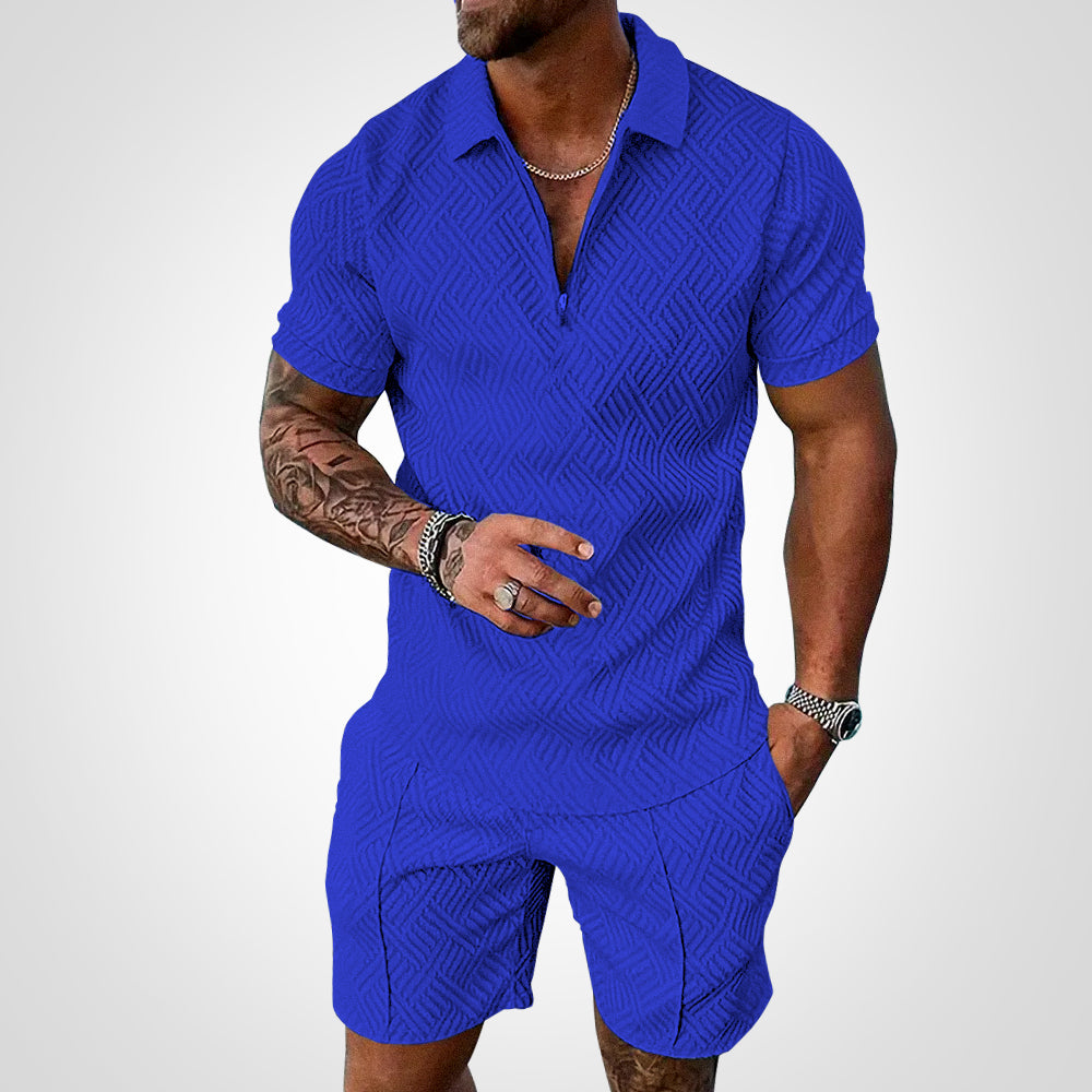 Mann in blauem, strukturiertem Kurzarm-Poloshirt und Shorts, tätowierter Arm, silberne Uhr und Kette, modischer Sommerlook.