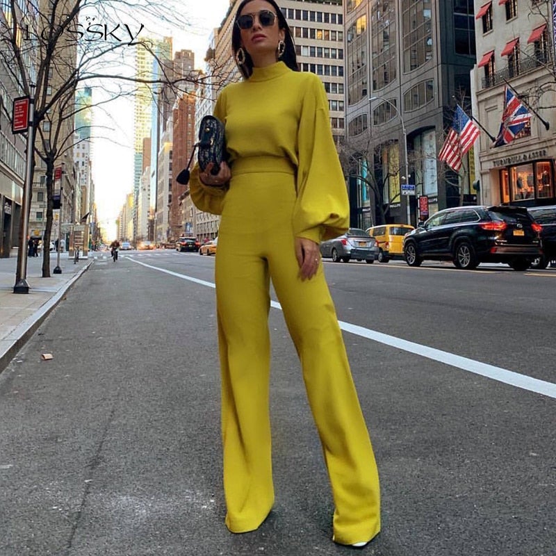 Frau in gelbem Outfit auf New Yorker Straße, hält schwarze Tasche, umgeben von Wolkenkratzern und gelben Taxis, Mode, Stadtleben, USA.