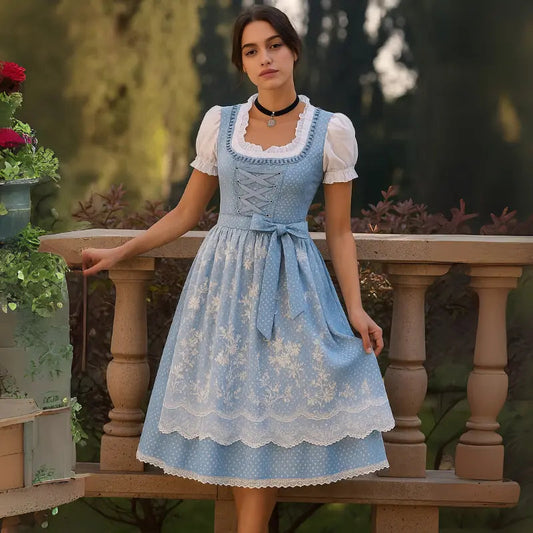 Frau in traditionellem blauen Dirndl mit weißer Bluse auf Balkon, umgeben von Pflanzen. Bayerische Tracht, Oktoberfest, Trachtenmode.