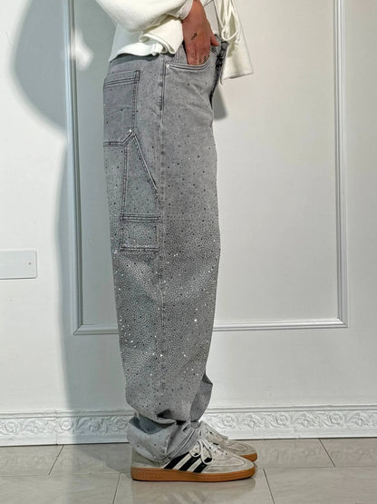 Graue Jeans mit Strasssteinen, seitlicher Tasche und weißen Adidas-Sneakern. Modetrend, Streetwear, Herrenmode, lässiger Stil.