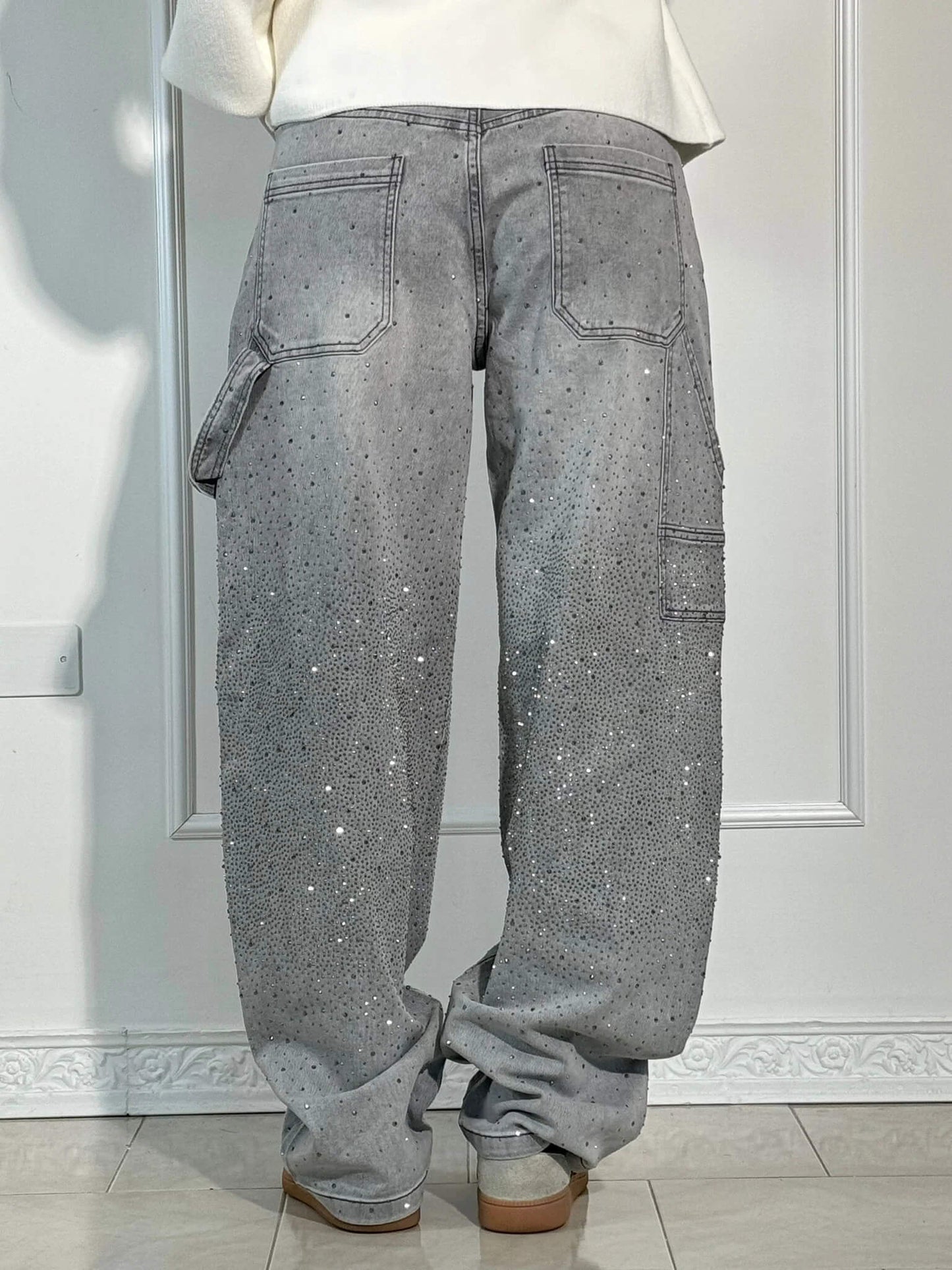 Graue Baggy-Jeans mit Strasssteinen, Rückansicht. Modetrend, lässiger Stil, funkelnde Details. Perfekt für urbanen Look und Streetwear.