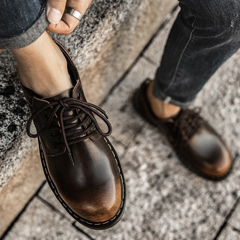 Braune Lederschuhe für Herren, geschnürt, auf grauem Steinboden. Stilvolle Herrenschuhe, ideal für Freizeit und Business. Elegante Fußbekleidung.