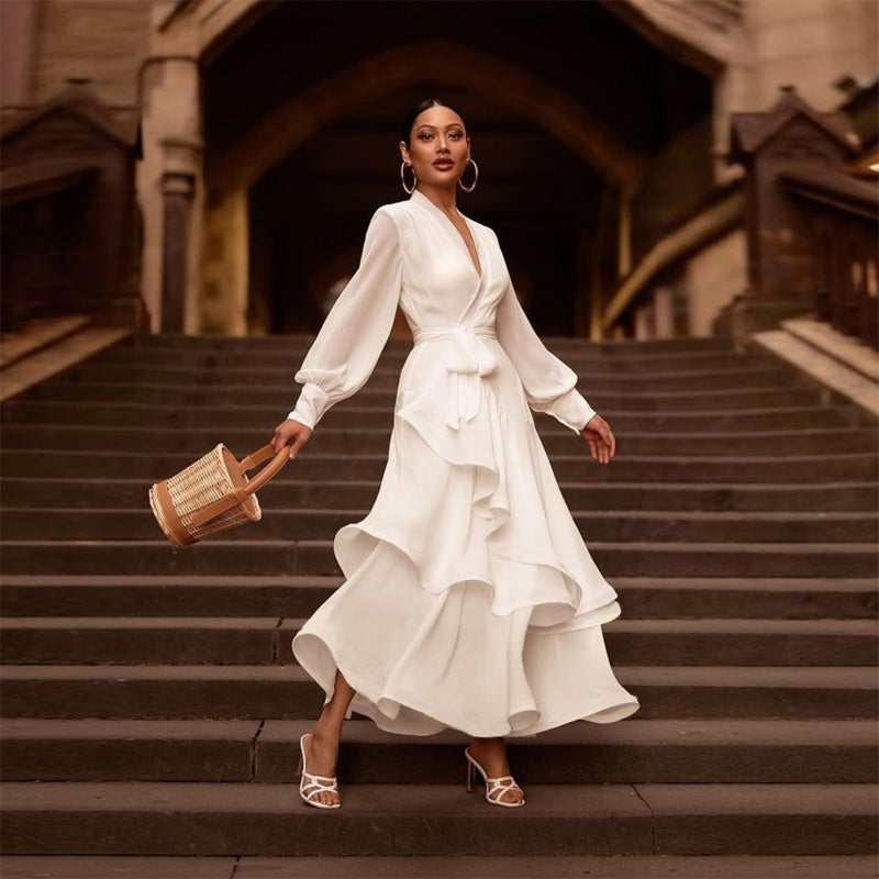 Elegante Frau in weißem Rüschenkleid auf Treppe, trägt Korbtasche und Ohrringe. Mode, Stil, Abendkleid, Damenmode, Accessoires.