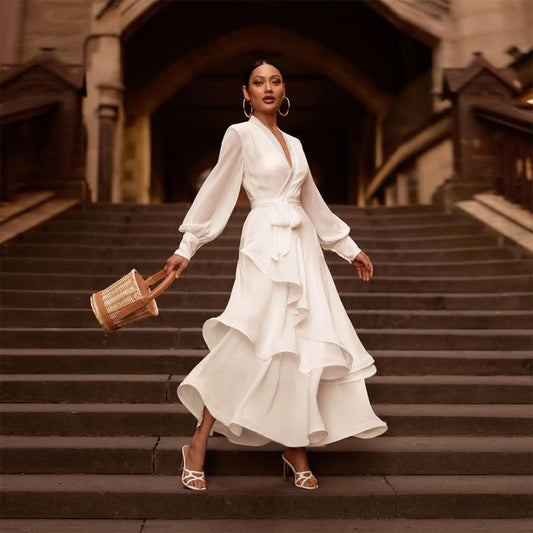 Elegante Frau in weißem Rüschenkleid auf Treppe, trägt Korbtasche und Ohrringe. Mode, Stil, Abendkleid, Damenmode, Accessoires.